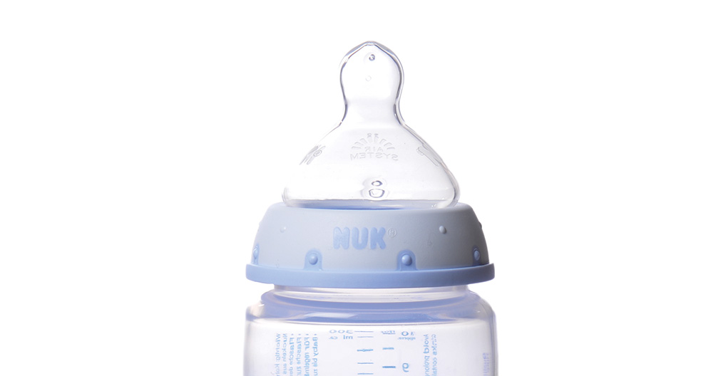 A baby bottle with a blue cap and a clear feeding nipple, marked with measurement lines.
