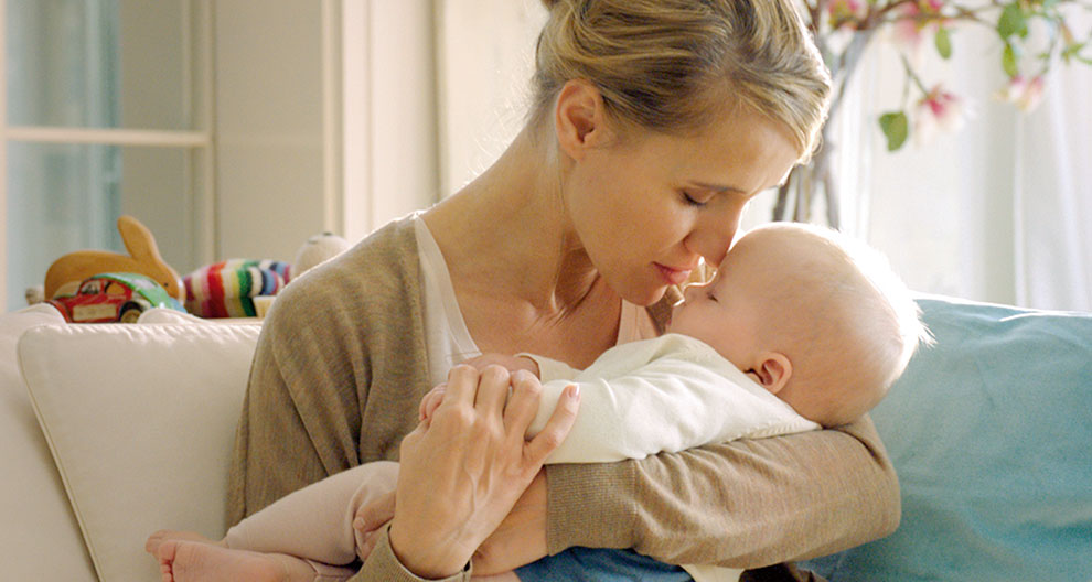 A woman is holding a baby close to her face.