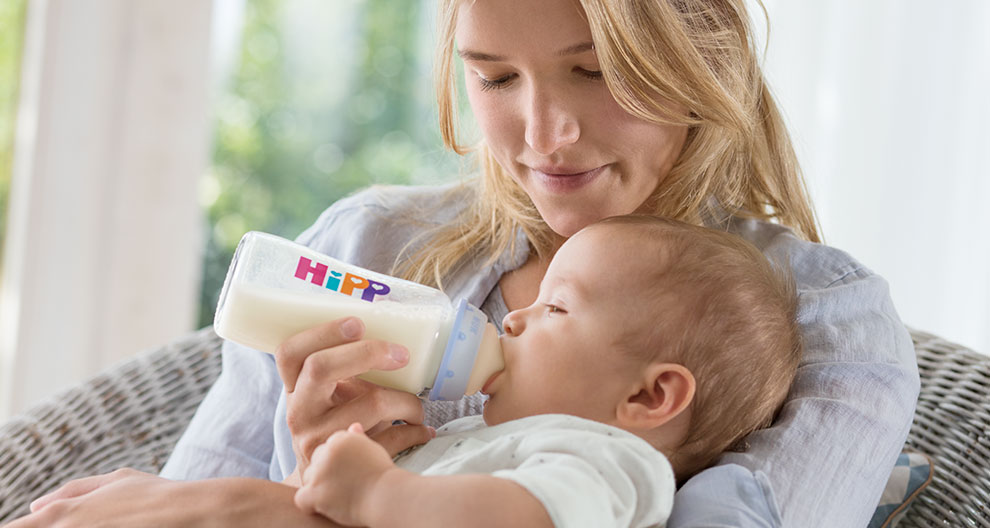 A woman feeds a baby with a Hipp bottle.
