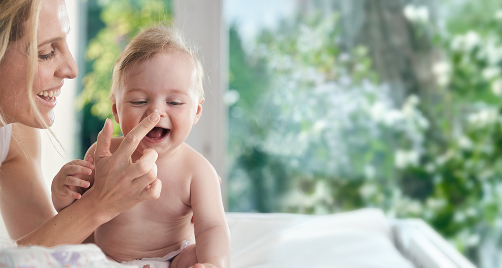A woman and a baby are engaged in a playful interaction.