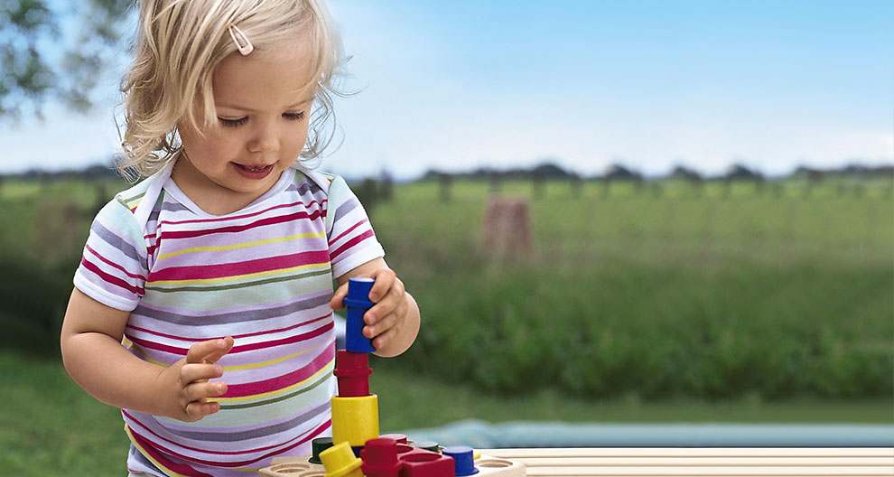 A young child is playing with colorful stacking blocks outdoors.