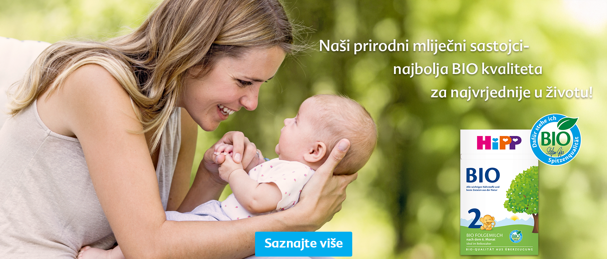 Žena s ljubavlju drži bebu, a s desne strane je kutija bioproizvoda.