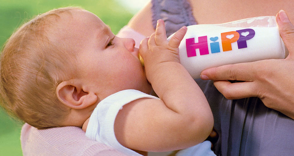 Beba pije iz bočice na kojoj piše "HiPP".
