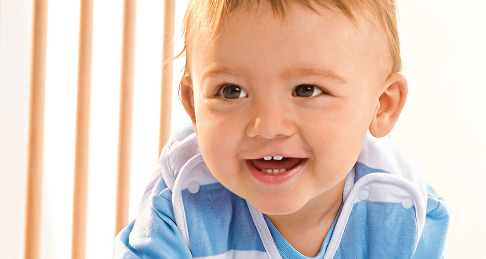 Dijete u plavo-bijeloj prugastoj majici gleda u stranu s osmijehom.
