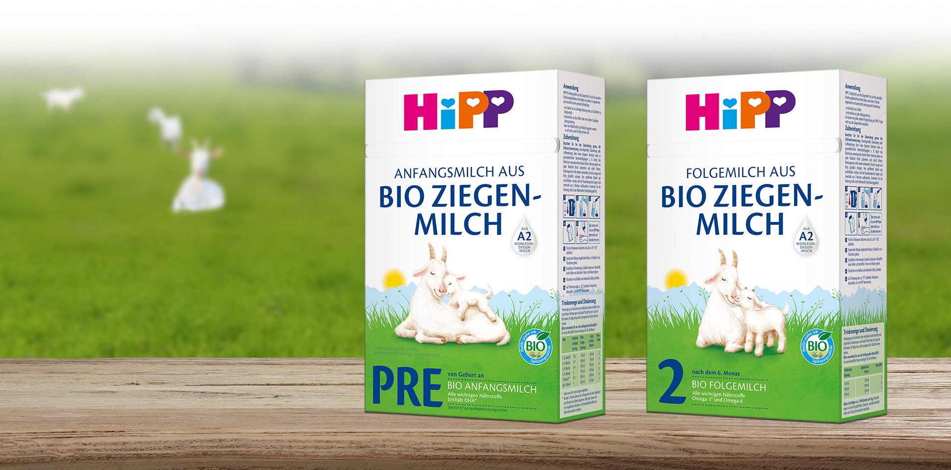 Dvije kutije Hipp dječje hrane izložene su na drvenoj površini, jedna označena kao Stage 1 Pre, a druga kao Stage 2, a obje na pakiranju imaju kozu i zeleni krajolik.