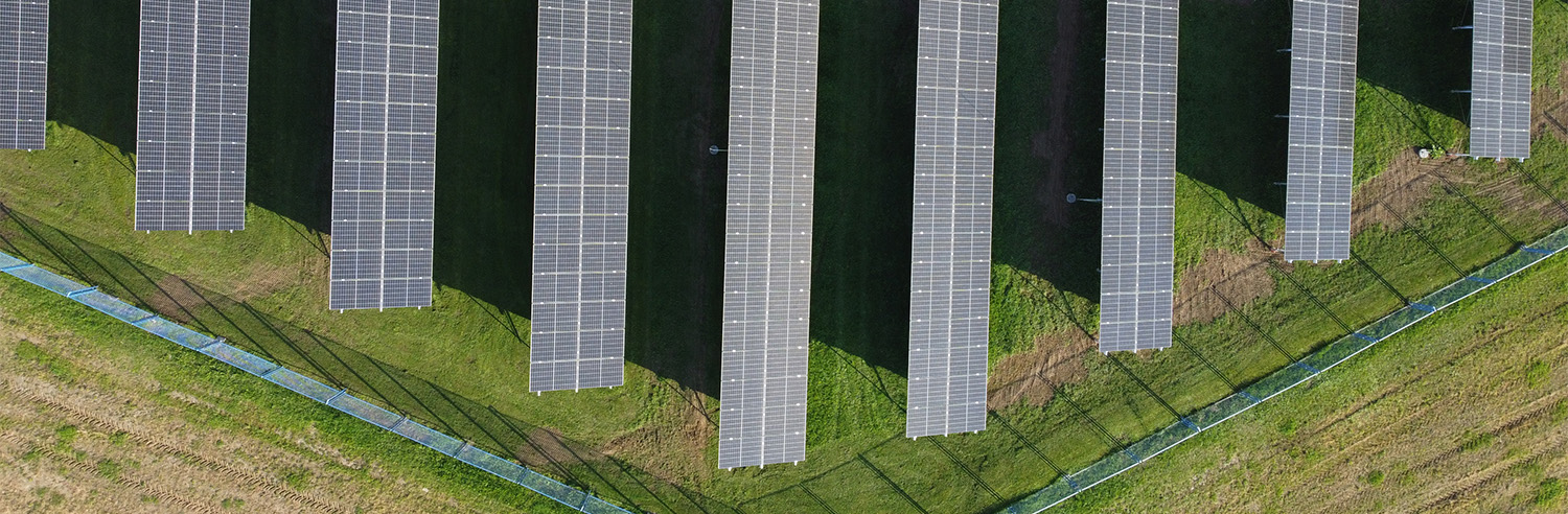 Zračni pogled na solarnu farmu s više solarnih panela poredanih u redove.