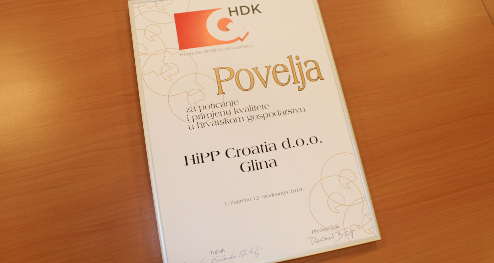 Uokvirena potvrda s natpisom "Povelja" nalazi se na drvenoj površini, a dodijeljena je tvrtki "HiPP Croatia d.o.o. Gliina" 2019. godine.